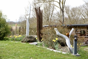 A garden with a white sculpture, a wooden structure, and yellow flowers. - Feuerstein - Kunsthof Salsitz (Lohme auf Rügen)