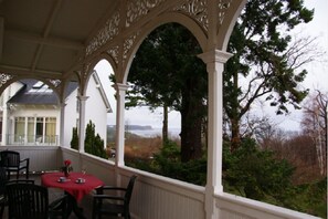 A covered outdoor area with a table and chairs, overlooking a natural landscape with trees and a distant view of a body of water. - Villa Granitz - Apartment 45463 Zum Donnerkeil - Apartment Zum Donnerkeil (Göhren)