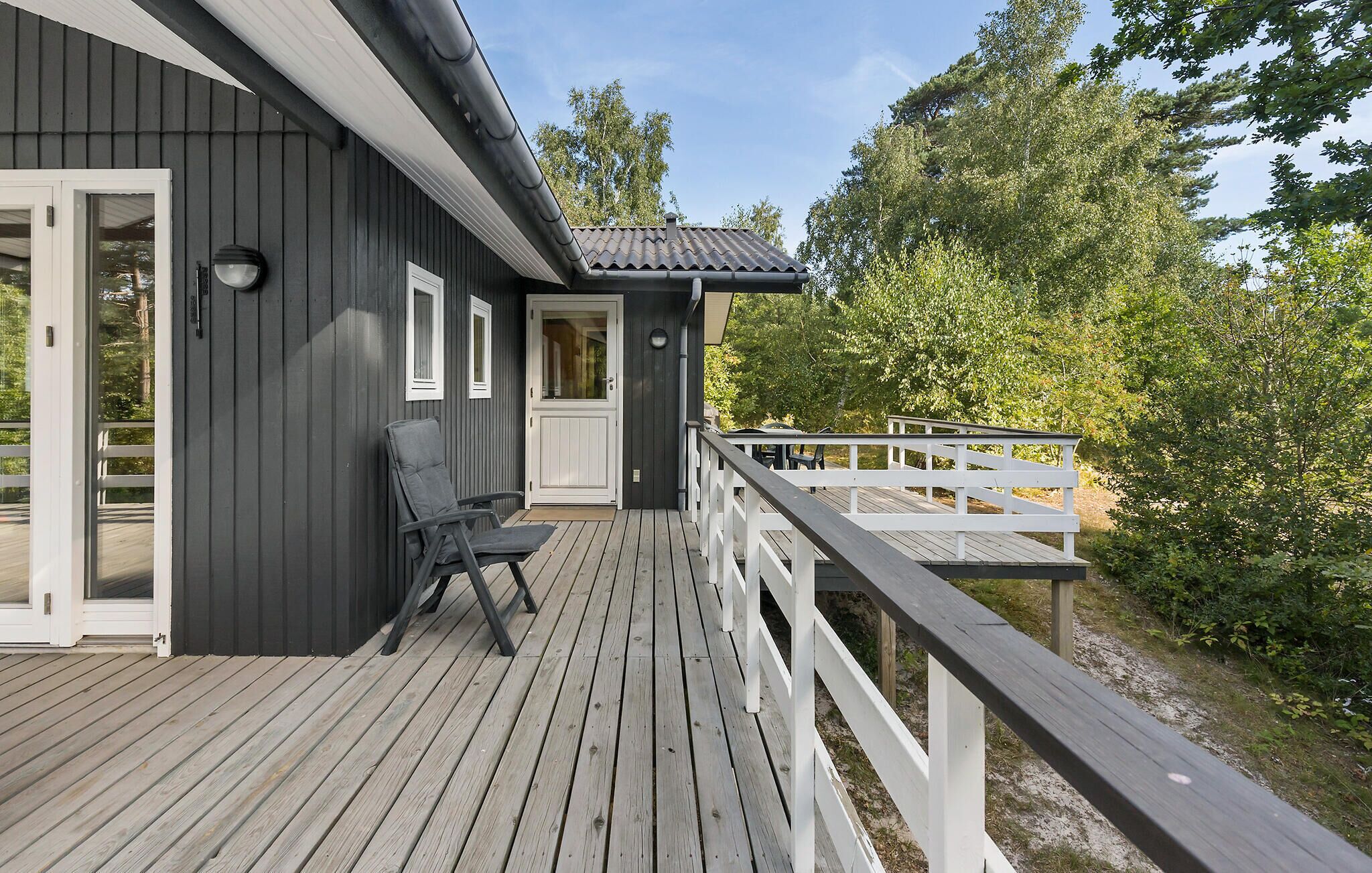 Une terrasse en bois avec une balustrade blanche, une porte et une fenêtre.