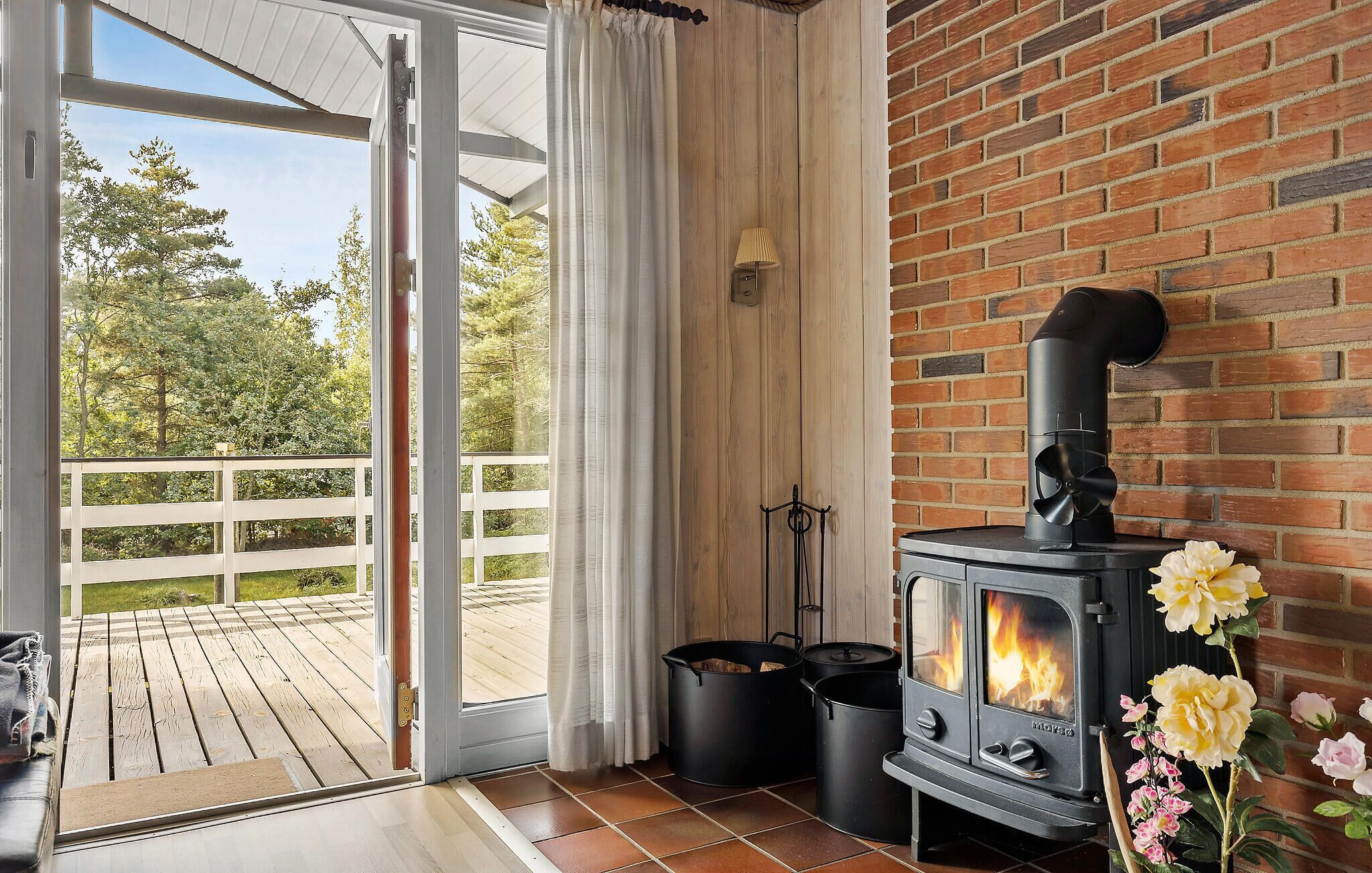 A room with a wood-burning stove, a sliding glass door to a deck, and a brick wall.