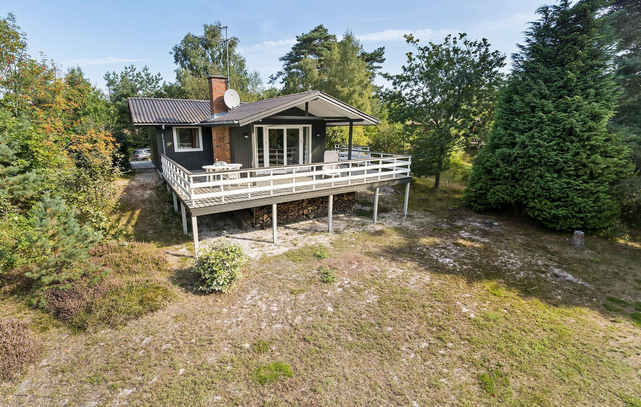Et toetagers hus med balkon, omgivet af træer og en græsplæde.