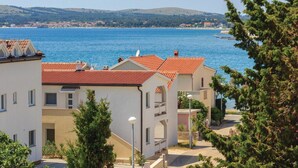 A coastal residential area with buildings featuring red-tiled roofs and a clear view of the sea.