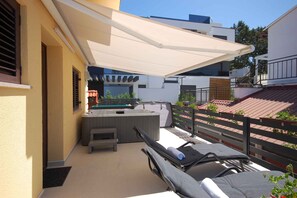 A balcony with a sun lounger, a small table, and a hot tub.