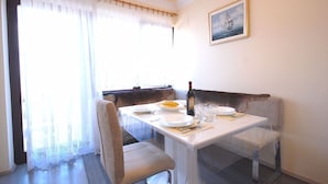 Un comedor con una mesa dispuesta para dos, un sofá y una ventana con cortinas.