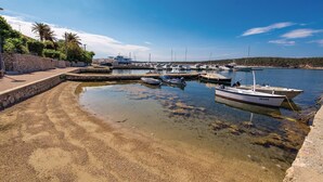 A marina with boats docked, a stone wall, and a clear sky.