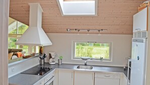 A modern kitchen with a skylight, a Bosch refrigerator, and a window with a view of greenery. - Awesome home in Væggerløse with sauna (Væggerløse)