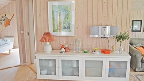 A room with a white cabinet with glass doors, a framed painting on the wall, a white lamp, and a small table with decorative items. - Awesome home in Væggerløse with sauna (Væggerløse)