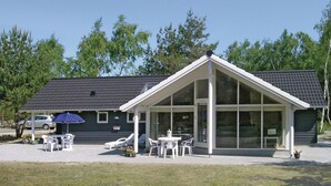 A modern building with a covered patio area, large windows, and outdoor seating. - Awesome home in Væggerløse with sauna (Væggerløse)