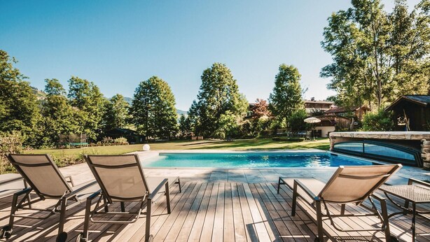 A wooden deck with lounge chairs and a swimming pool. - Ferienwohnung in Wagrain (Wagrain)