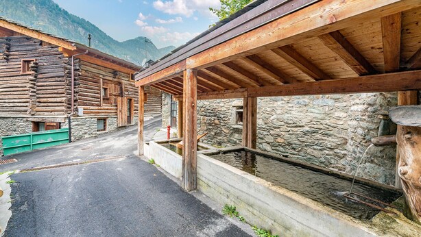 Un edificio rústico de madera con un muro de piedra y estructura de techo de madera.