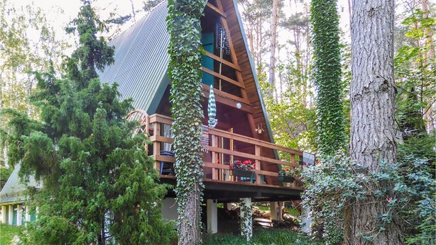 A cabin with a sloped roof, wooden balconies, and surrounded by trees. - 2 bedroom stunning home in Mragowo (Mragowo)