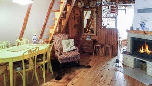 A cozy wooden interior with a dining table, chairs, a patterned armchair, a fireplace, and a staircase. - 2 bedroom stunning home in Mragowo (Mragowo)
