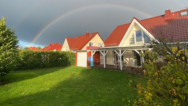 A row of houses with red roofs and a rainbow in the background.