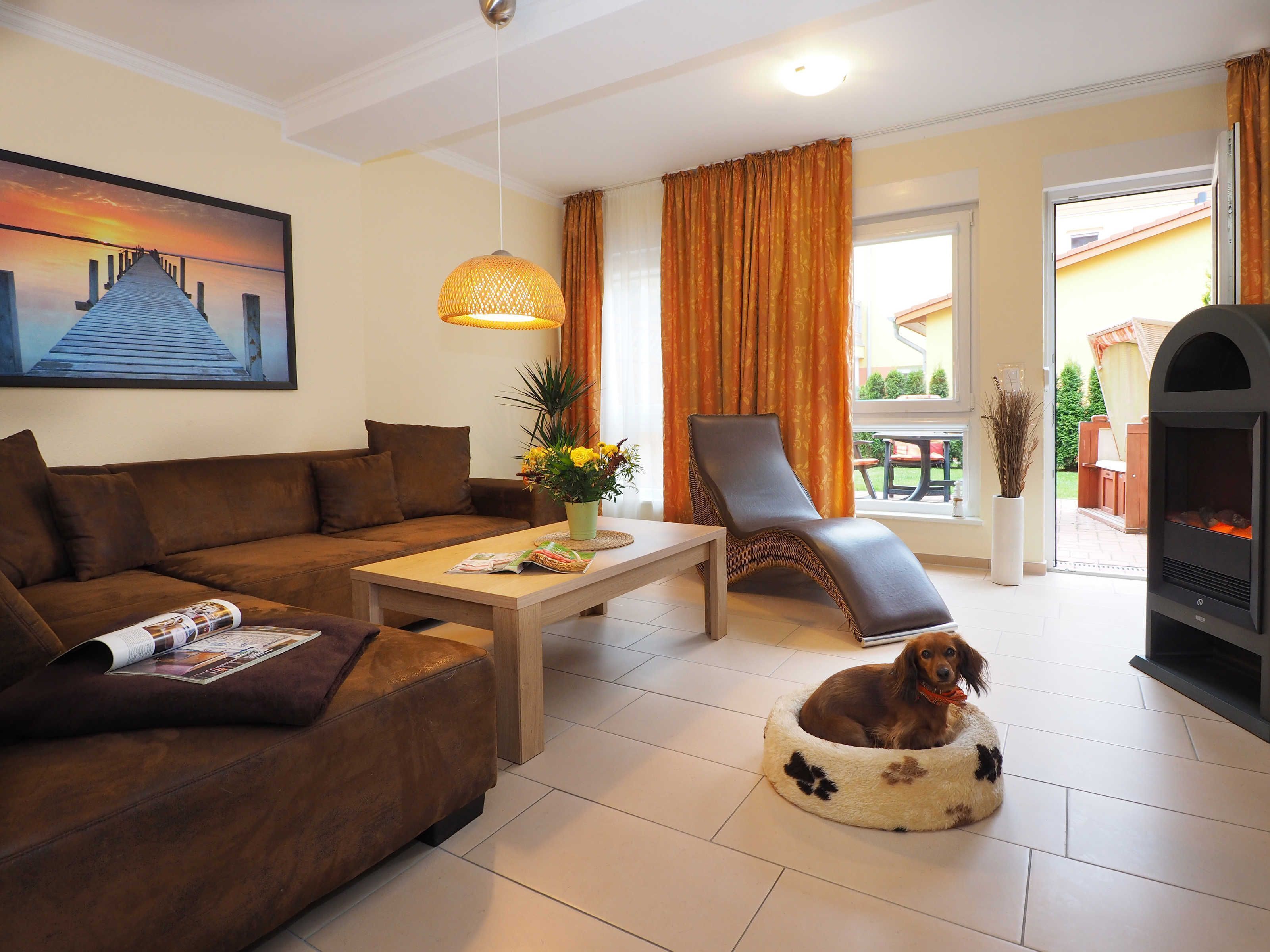Un salon avec un canapé, une table basse, un panier pour chien, une cheminée et un tableau au mur.