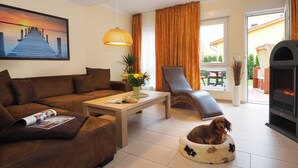 A living room with a sofa, a coffee table, a dog bed, a fireplace, and a painting on the wall.