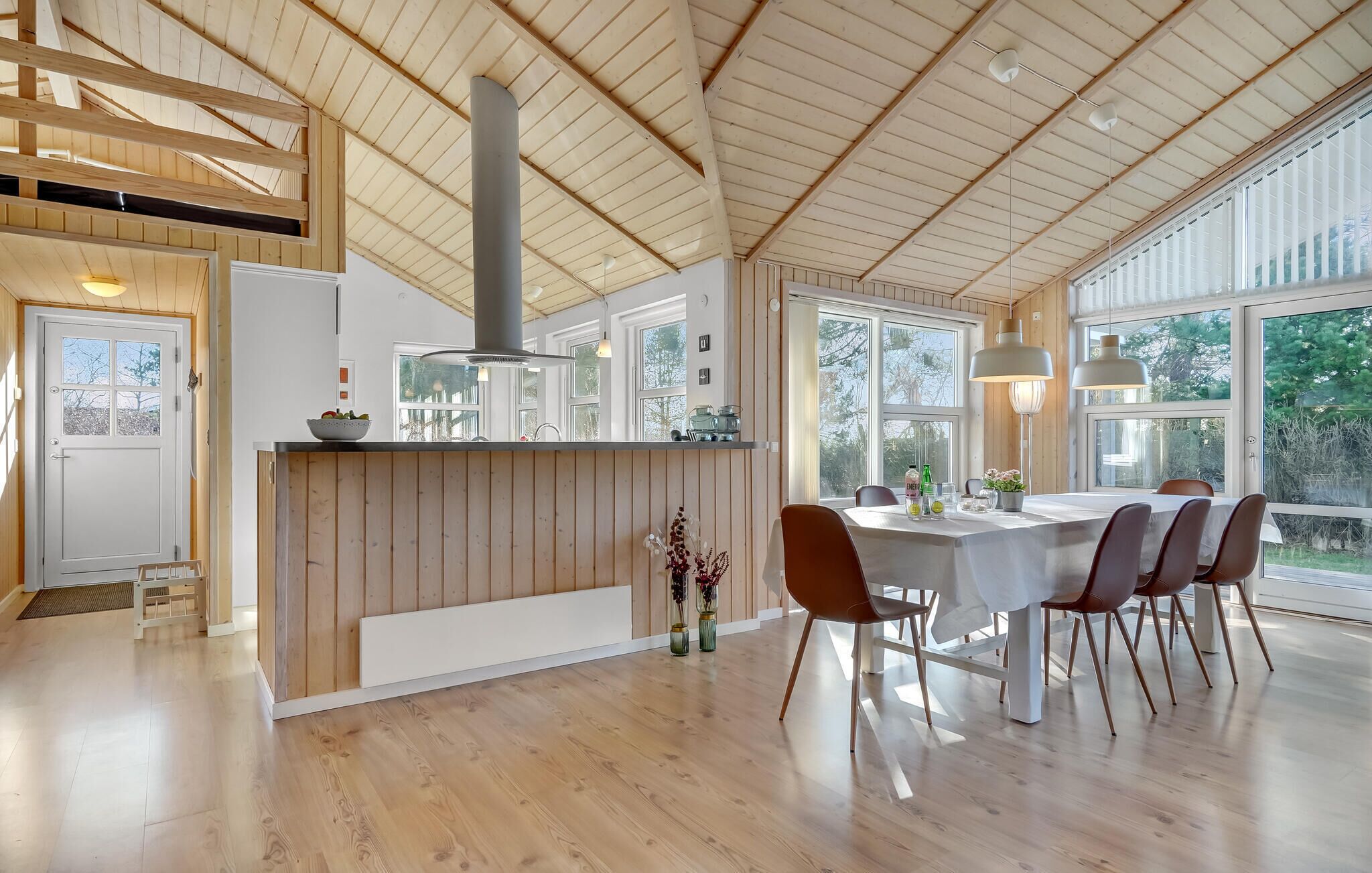 A spacious kitchen with a central island, large windows, and a dining area with a table and chairs.
