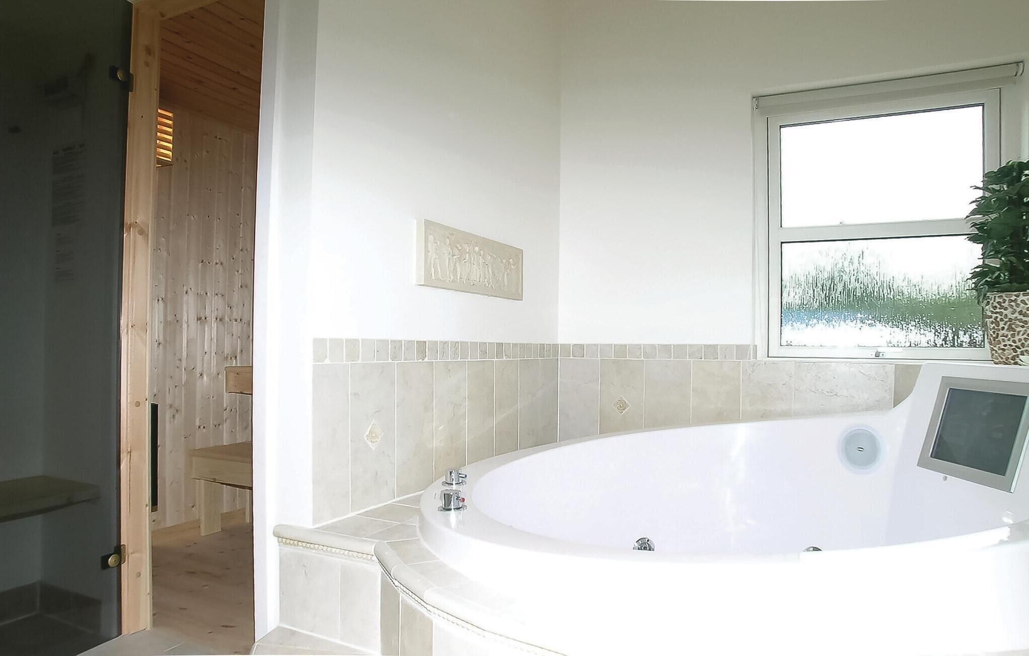 Une salle de bain moderne avec une baignoire sur pieds, une fenêtre offrant une belle vue et une porte en bois.