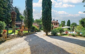 A gravel driveway leading to a house with a pool area, surrounded by various trees and plants. - Luxurious home in Scarlino (GR) (Scarlino (GR))