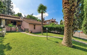 A residential property with a well-maintained lawn, a stone pathway, and a palm tree. - Luxurious home in Scarlino (GR) (Scarlino (GR))