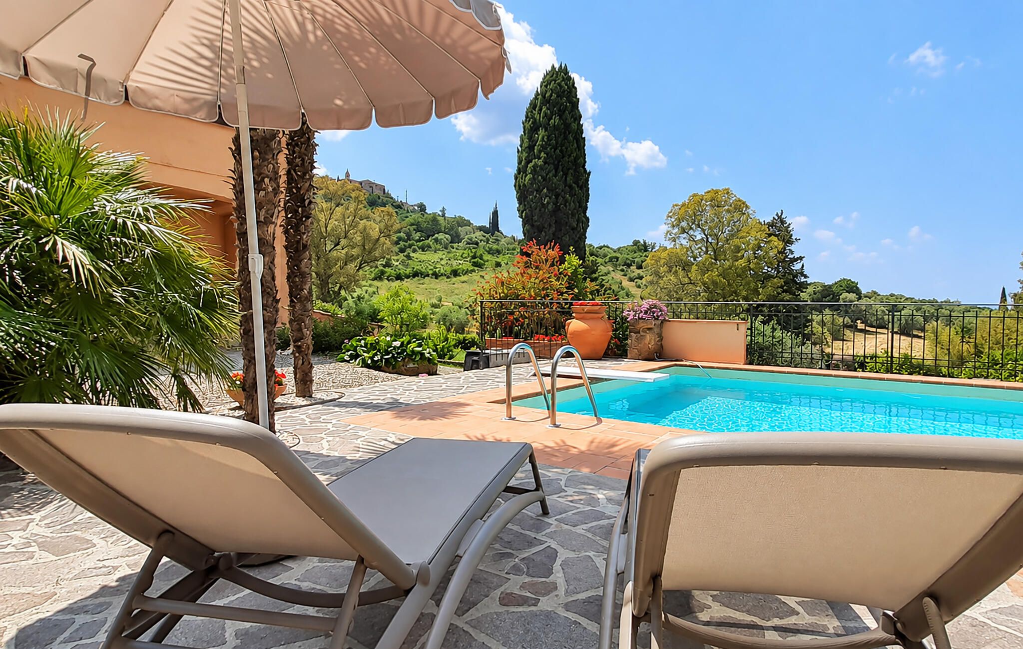 Area piscina con lettini, piscina e vista su un paesaggio collinare.