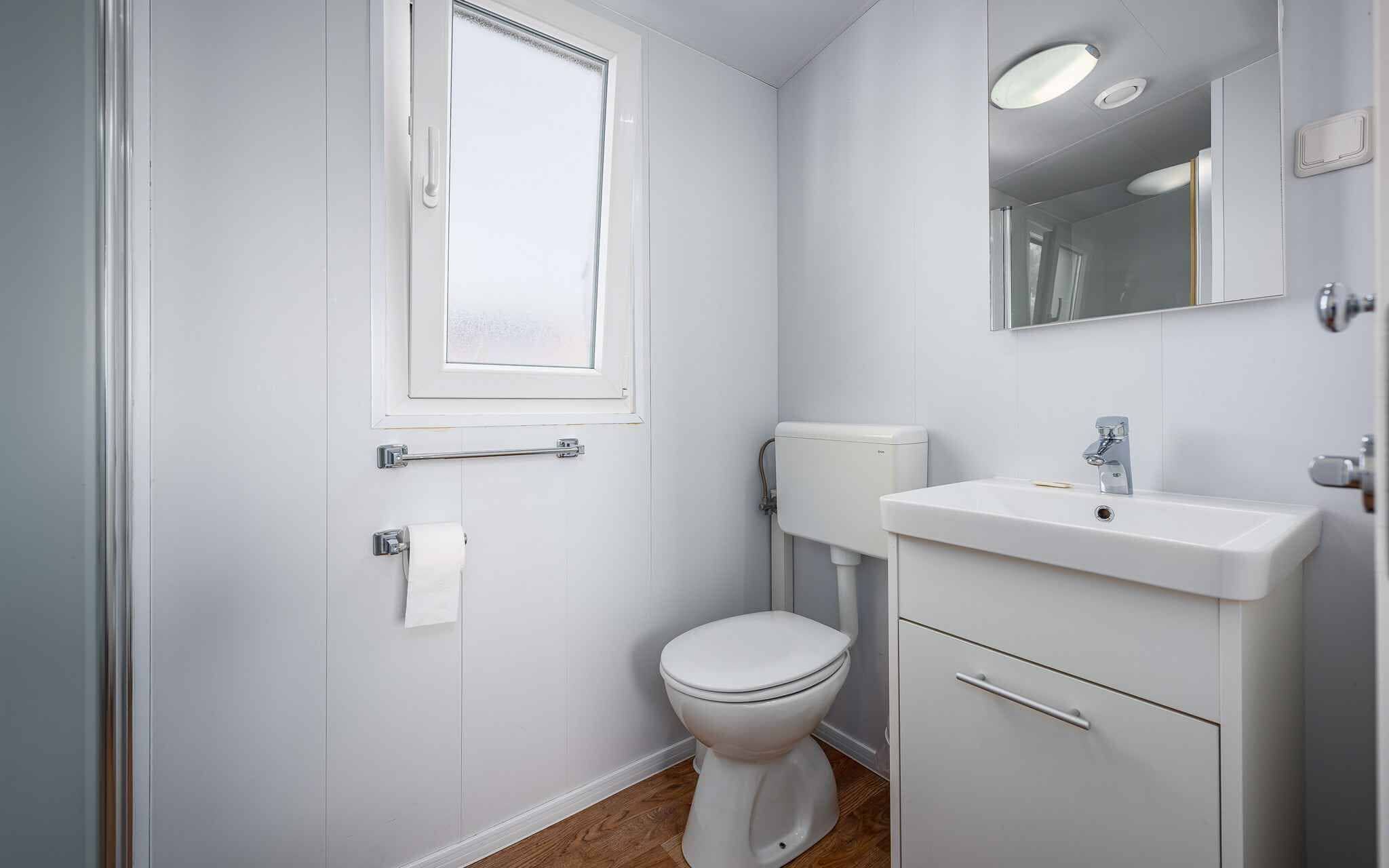 Un baño pequeño y blanco con inodoro, lavamanos y espejo.