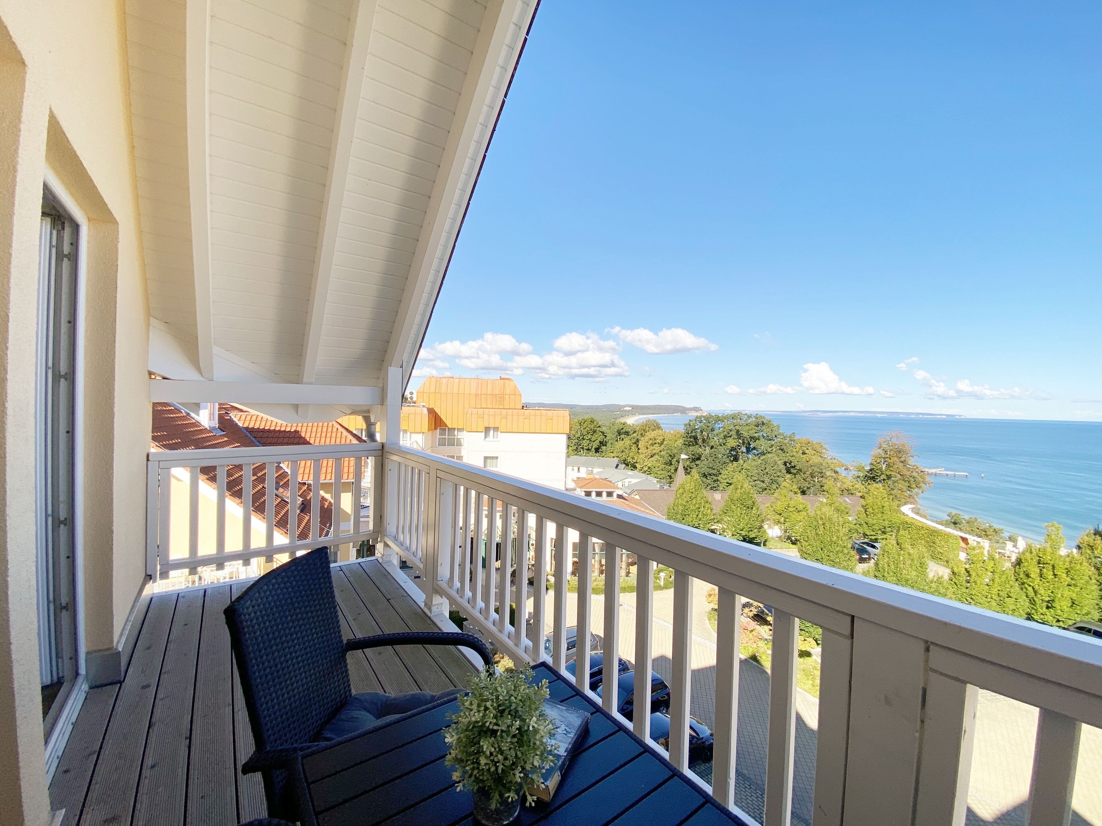 A balcony with a view of the sea, a chair, and a potted plant.