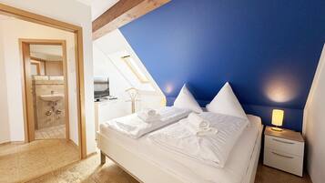 A bedroom with a bed, a nightstand, and a skylight.