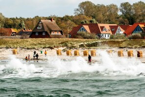 A coastal village with traditional houses, a sandy beach, and waves crashing onto the shore.