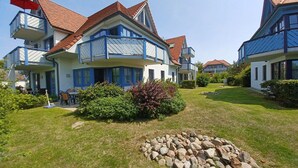 Ein zweigeschossiges Wohnhaus mit Balkon, Rasen und einer Steinmauer.