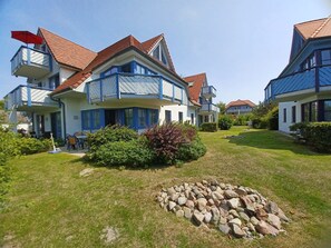Ein zweigeschossiges Wohnhaus mit Balkon, Rasen und einer Steinmauer.