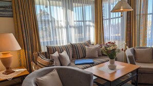 Ein gemütliches Wohnzimmer mit einer Couch, Sesseln, einem Couchtisch und einer Lampe.