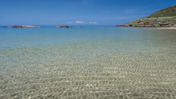 A clear beach with shallow water, rocky outcrops, and a distant coastline. - 3 bedroom cozy home in Costa Rei -CA- (Costa Rei -CA-)