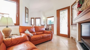 A living room with a leather sofa, a lamp, and a television. - 3 bedroom cozy home in Costa Rei -CA- (Costa Rei -CA-)