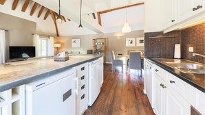 A modern kitchen with wooden beams, a dining area, and a TV. - Nice apartment in Ocquerre with swimming pool (Ocquerre)