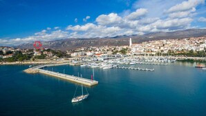Une ville côtière dotée d’un port de plaisance, d’une tour imposante et bordée par une chaîne de montagnes.