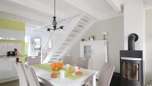 Una cucina moderna con zona pranzo, mobili bianchi, una scala e una stufa a legna.