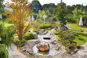 A garden with a pond, rocks, and a wooden bridge.