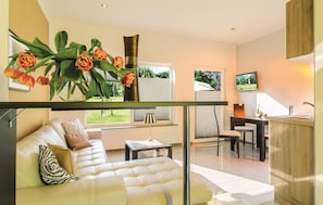 A modern living room with a sofa, a dining table, and a kitchen area. - 2 bedroom amazing home in Pinnow (Pinnow)