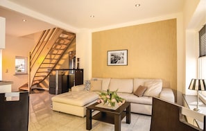 A modern living room with a staircase, a sofa, a coffee table with flowers, and a framed picture on the wall. - 2 bedroom amazing home in Pinnow (Pinnow)