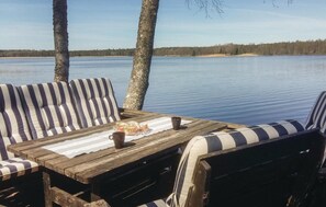 Une terrasse en bois, agrémentée de meubles d’extérieur à rayures, donnant sur un lac paisible.