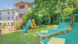 A garden with a slide, lounge chairs, and a building in the background. - Cozy home in Valpromaro-Camaiore LU (Valpromaro-Camaiore LU)