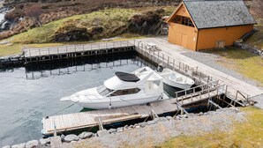 Un bateau blanc était amarré à un quai en bois, près d’un petit bâtiment également en bois.