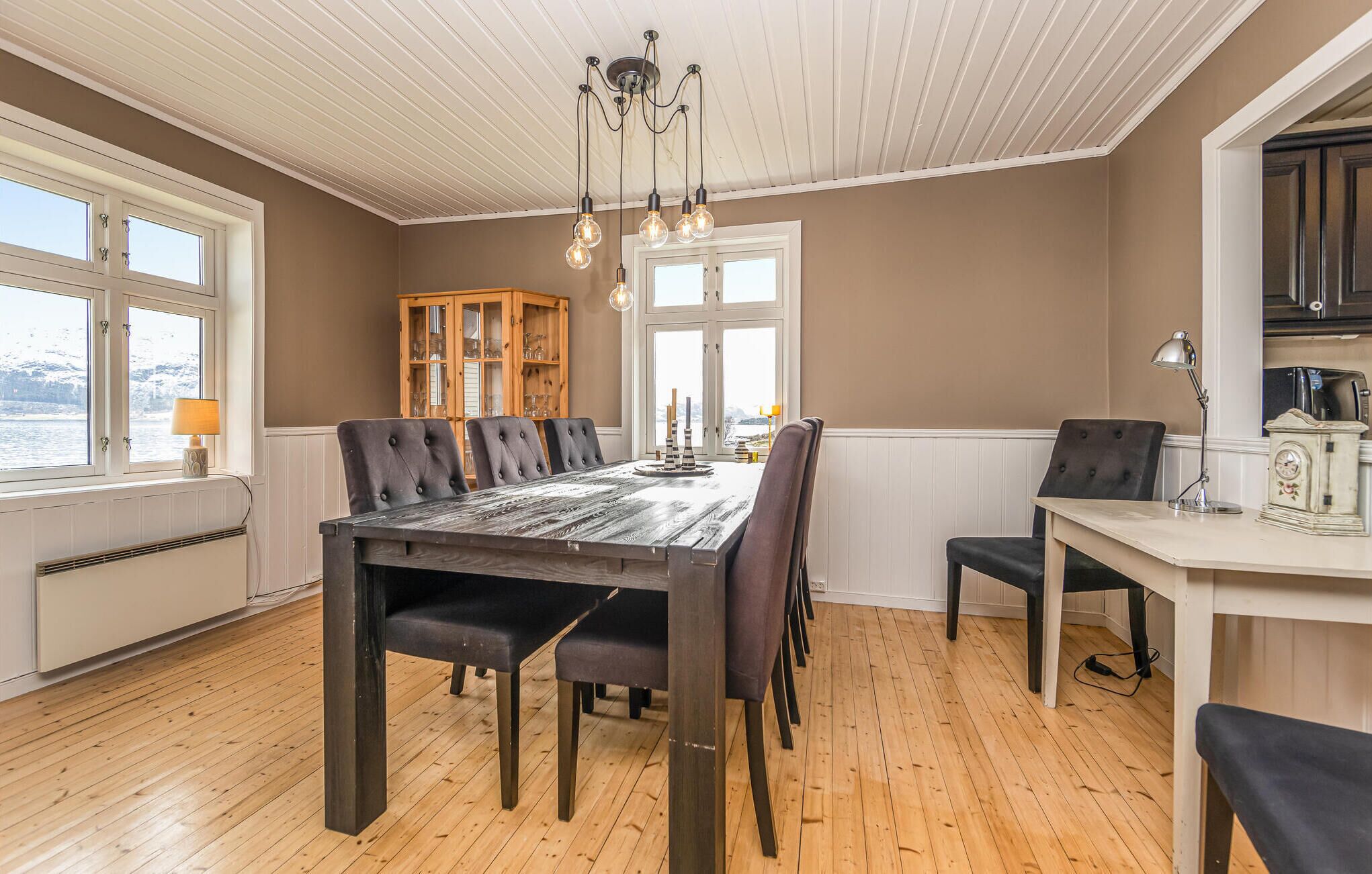 Ein Essbereich mit Holztisch und -stühlen, einem Schrank und Blick durch die Fenster.