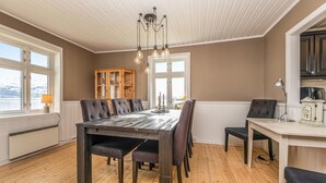 Un coin repas avec une table et des chaises en bois, un buffet et une vue par les fenêtres.