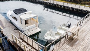 Un port de plaisance avec un bateau amarré, un plus petit bateau et une passerelle en bois.