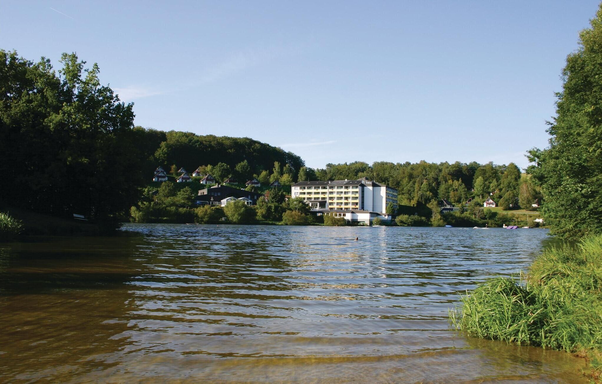 A lake with a hotel in the background surrounded by trees.