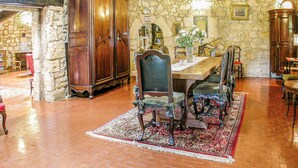 A dining area with a stone wall, wooden furniture, and a traditional rug. - Stunning home in Cézac (Cézac)