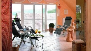 A sunlit room with a view of the sea, featuring a table with drinks, a statue, and a chair. - Room type A - Double room - Flair Hotel Werbetal (Waldeck)