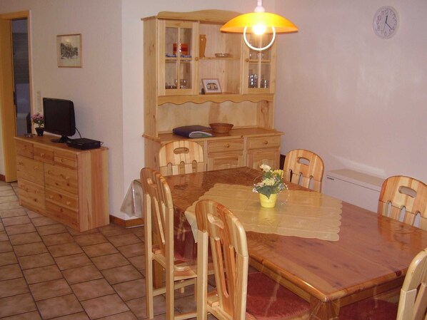 Un comedor con una mesa de madera, sillas, un armario y un reloj en la pared.