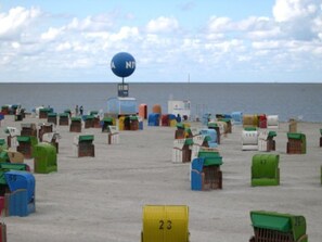 Una playa con numerosos contenedores numerados, una torre de salvavidas y una vista despejada del mar.
